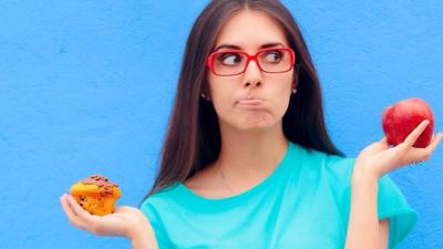 Stock image of a woman holding a muffin and an apple