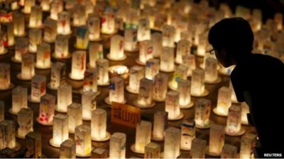 A boy looks at candles during a candlelit memorial event to mourn the victims of the 1945 atomic bombing at Nagasaki"s Peace Park in western Japan