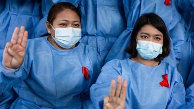 Female healthcare workers in Myanmar showing the three-fingered salute