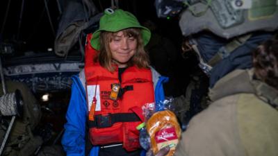 Greta Thunberg in green hat and red life jacket