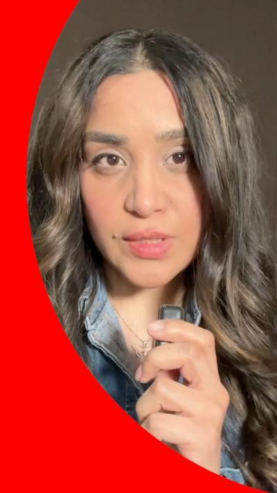 Woman with long dark hait and denim jacket holding small mic