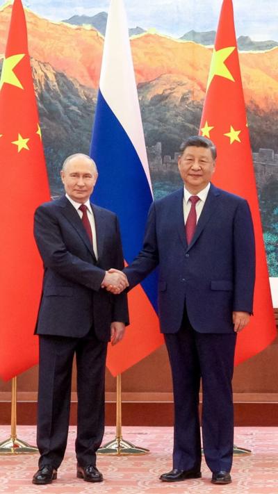 Putin and Xi shaking hands in front of Russian and Chinese flags