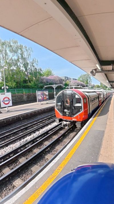 The front of a new Piccadilly line train in London. The Tube train pulls in slowly to a platform. On it's front - a thin white glowing strip surrounding the drivers' cabin.