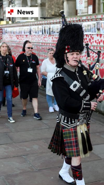 A man plays the bagpipes near the National Covid Memorial Wall on the COVID-19 Day of Reflection,