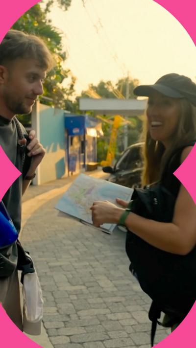 A man and a woman stands on a street in the sunshine