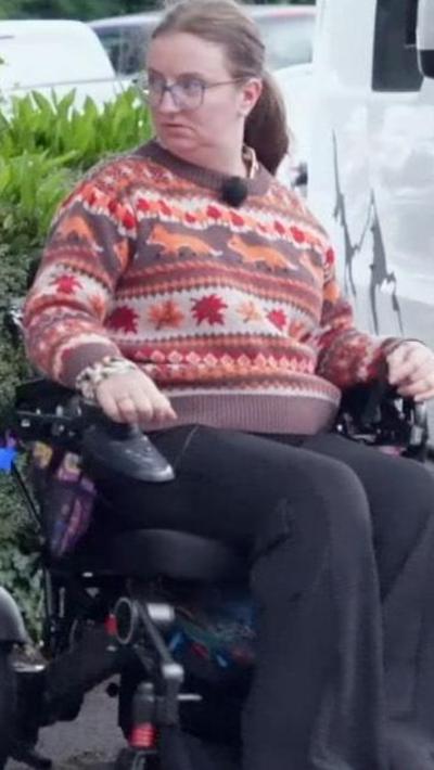 Woman in a wheelchair wearing a pattern jumper 