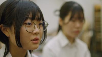 A Hiroshima student wearing glasses is interviewed.