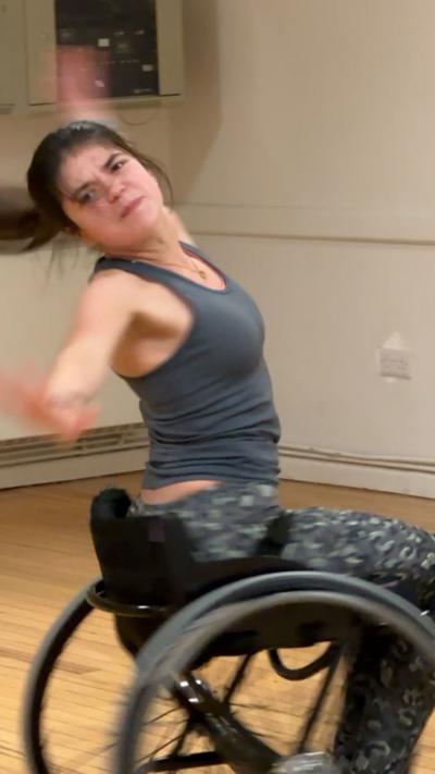 A girl in a grey top dances in a wheelchair.