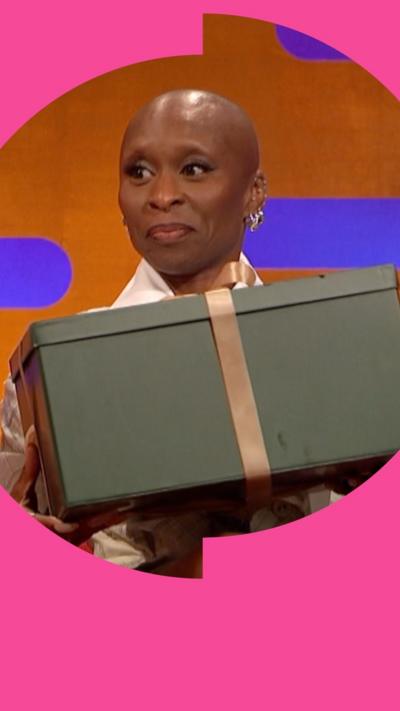 Cynthia Erivo holds a green gift box with a gold ribbon. 