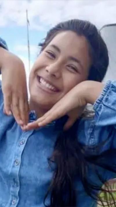 Young woman with long dark hair smiles as she jokes for the camera.