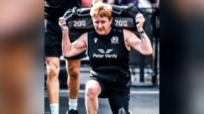 Woman holding 20kg weight while lunging. She has brown/ginger short hair.