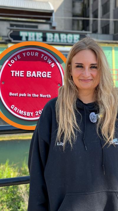 Woman standing in front of a red plaque for The Barge in Grimsby.