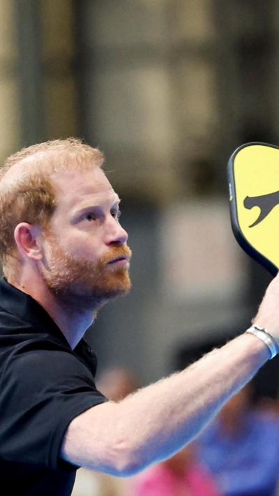 A man with a ginger beard and hair holding a black and yellow racquet and wearing a black shirt