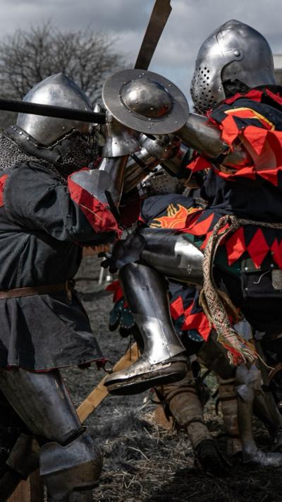 People in medieval armour fighting with swords. 
