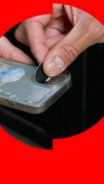 A person puts a sticker over a phone's camera