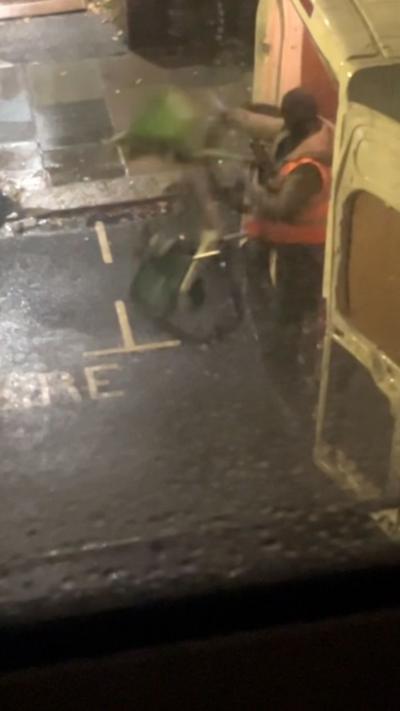 A man in a high vis throws a green bike to the floor from a van.