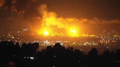 Skies over LA county bright orange as oil refinery burns in the background.