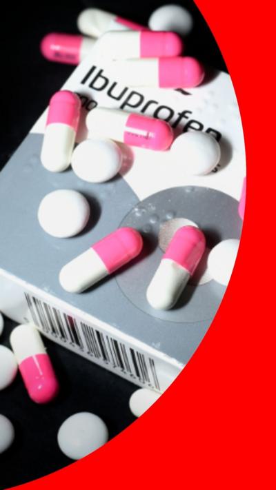Box of ibuprofen with red and pink capsules and white tablets sprinkled on top.