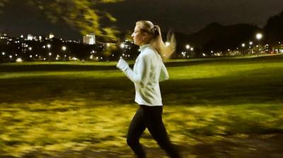 Side view of a woman in casual wear running in a park in the evening