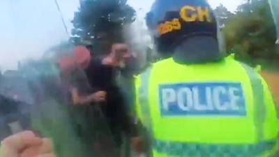 A man fighting with police carrying riot shields