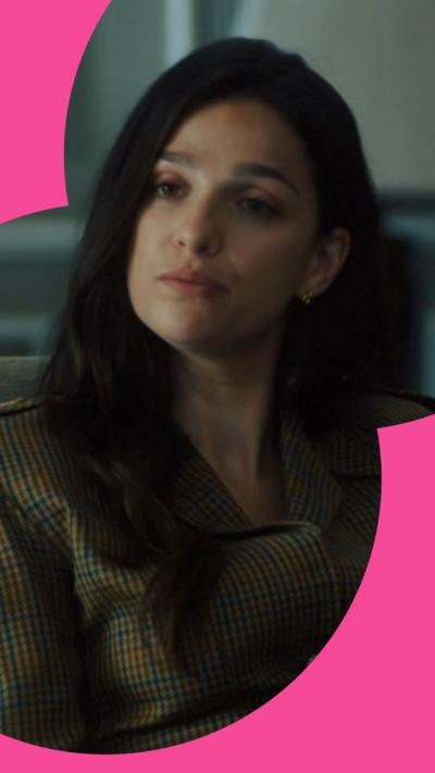 A woman with dark brown hair dressed in business attire listens during a conversation.