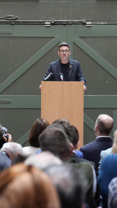 Andy Burnham speaking at podium 
