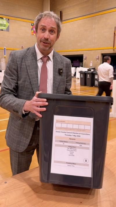 Election count supervisor in Clacton stands with a ballot box
