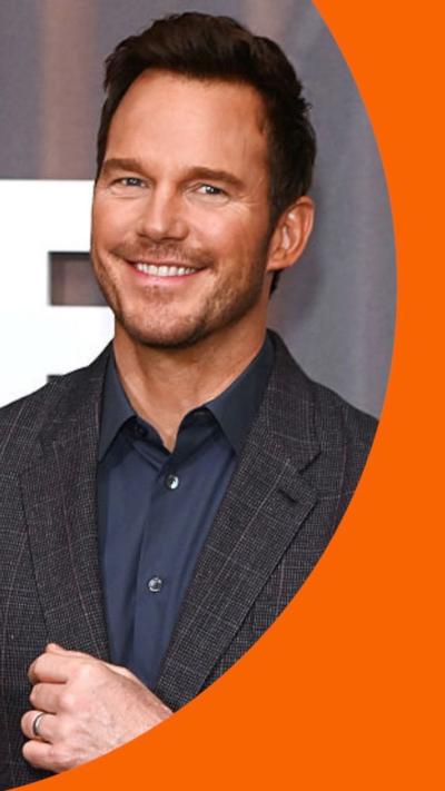 Chris Pratt wearing dark suit and smiling to camera.