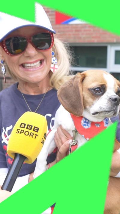 An American woman wearing a white cap and sunglasses holds her dog to the camera.