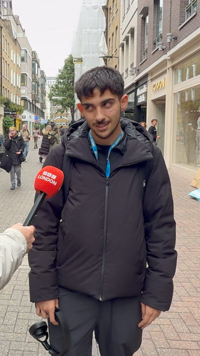 A young man speaks into a BBC London microphone about driverless cars. He is stood in London's Carnaby street