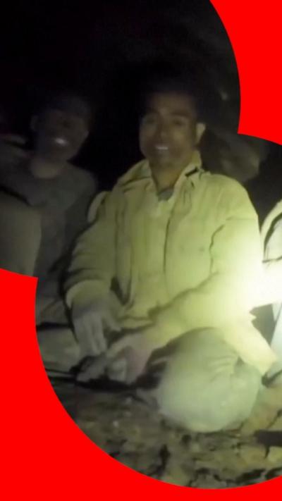 A man is illuminated by a yellow spotlight in a cave