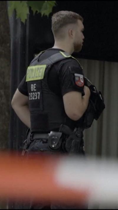 German police officer standing guard in front of police tape