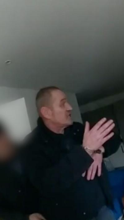 A man in handcuffs is being held by a police officer.