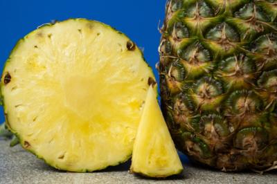 Close up view of pineapple cut in half with a wedge of the fruit