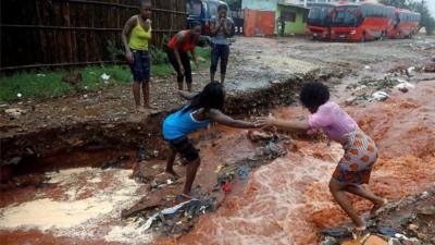 Two women try and cross a road in Pemba, Mozambique