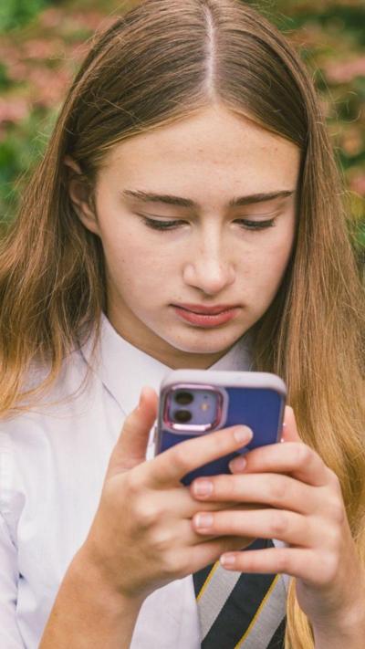 A young girl looks at her mobile phone