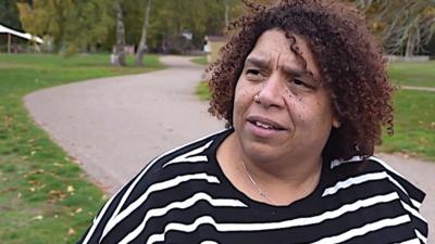 Woman at Sandringham estate with path and woods behind her, looking at the camera.