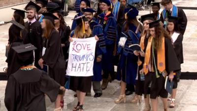 Students, one holding a banner reading "Love Trumps Hate" leave as Mike Pence begins to speak at graduation ceremony (21 May)