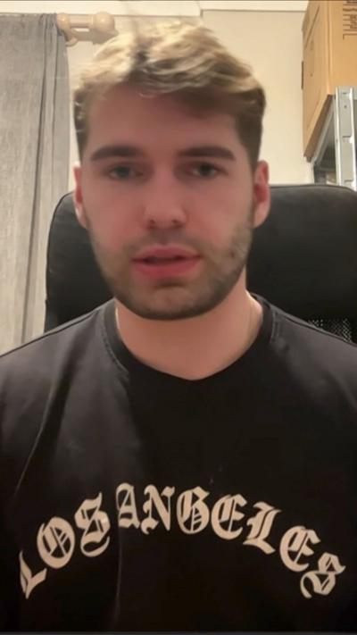 A young man wearing a dark top that says Los Angeles