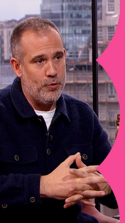 A man in a blue shirt with his hands clasped in front of him