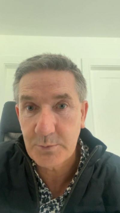 A man with short grey hair is looking into the camera