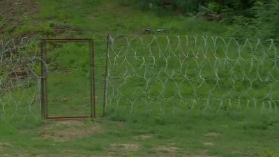 A small gate in the fence, along the Hungary-Serbia border, with no razor wire above it