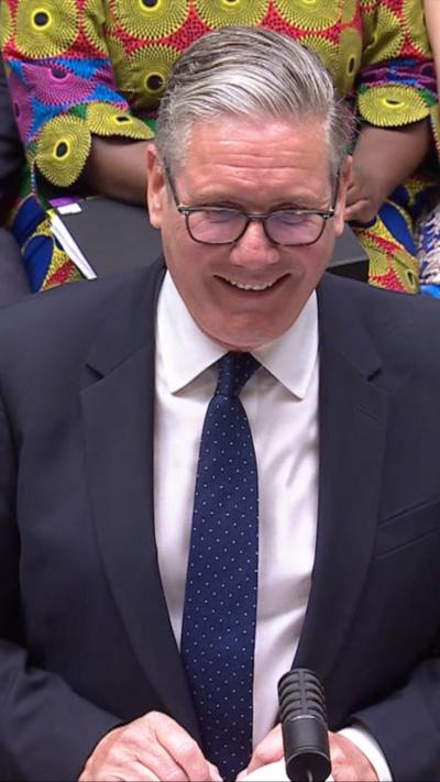 Starmer smiling in the House of Commons as he speaks