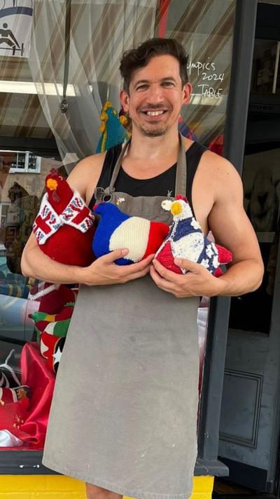 Stuart Race, owner of the Woolpatch shop, with the previous Olympi'hens that were knitted for the Olympics in 2024