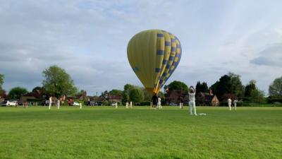 Hot air balloon in cricket field.