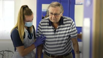 Man being helped to walk by a nurse