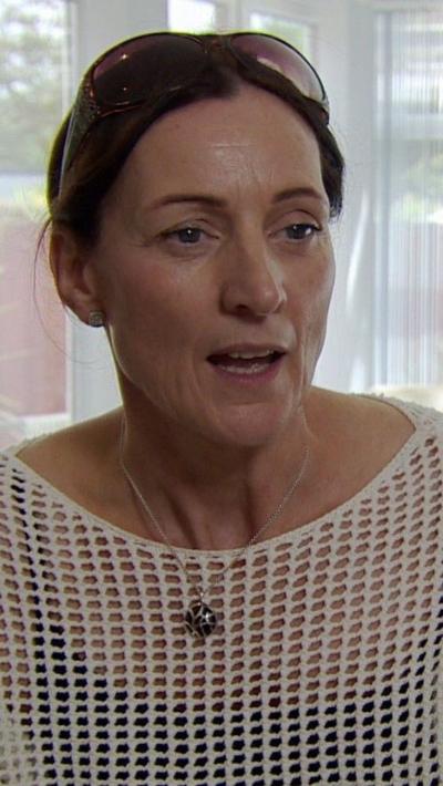 a woman in a crochet top with a necklace on, speaking