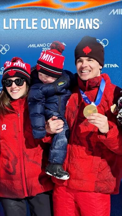 Mikael Kingsbury holding his child in one arm and gold medal in his other hand