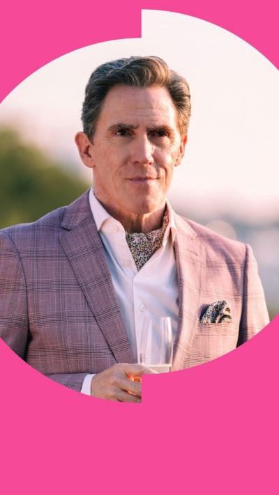 Rob Brydon holding a glass of fizz