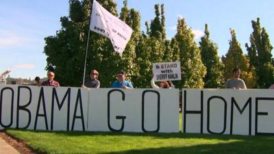 Protestors hold an 'Obama go home' sign